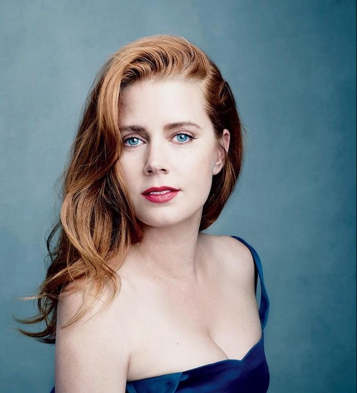 Amy Adams su raudonais plaukais, variniai šoniniai plaukai su nedidelėmis bangomis, tamsiai mėlyna suknelė