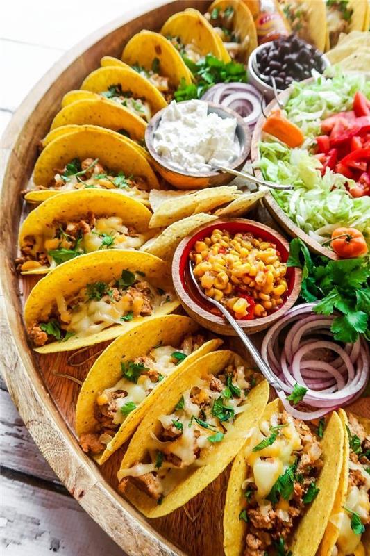 mini predjedi tacos s piščancem, kremnim sirom in sesekljanim peteršiljem, krožnik s taco grižljaji, različne omake in solate