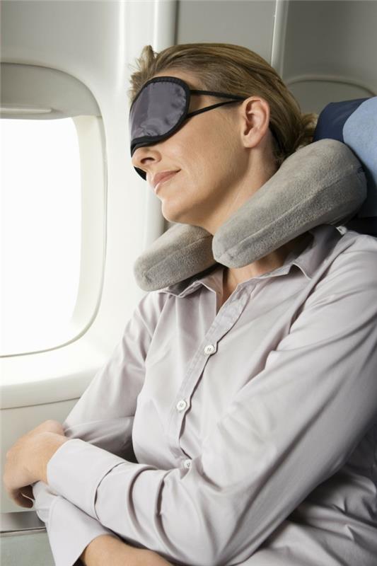 Lėktuve mieganti moteris, užsidėjusi akių kaukę