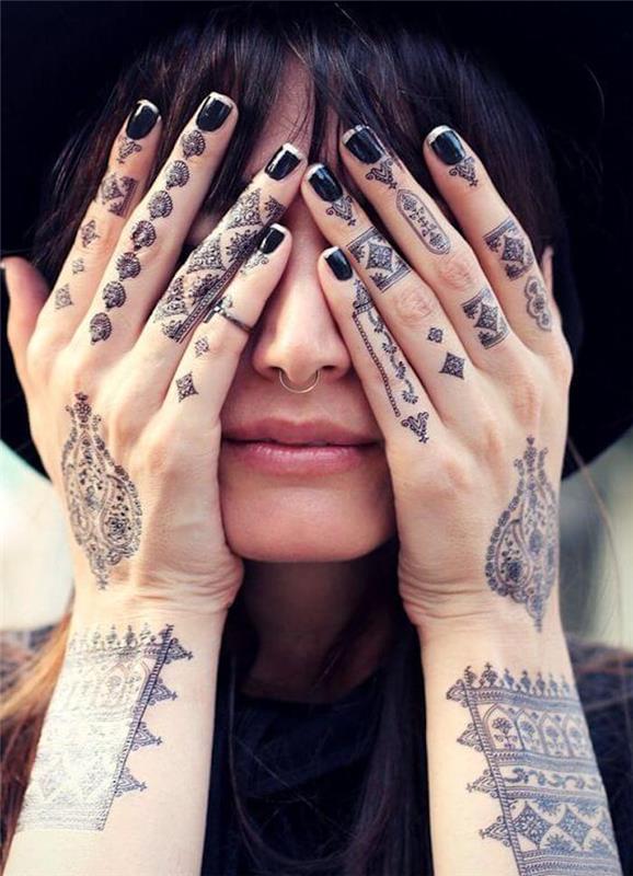 Mano tatuate di una donna con simboli e disegni mandala