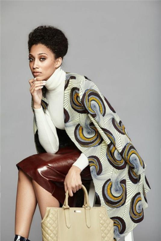 elegantiškas aprangos stilius, afrikietiškai ruda odos sijonas, afrikietiška mada, megztinis su vėžlio kaklu, baltas, palto tipo striukė su apvaliomis dekoratyvinėmis rudos, juodos ir geltonos spalvos aplikacijomis