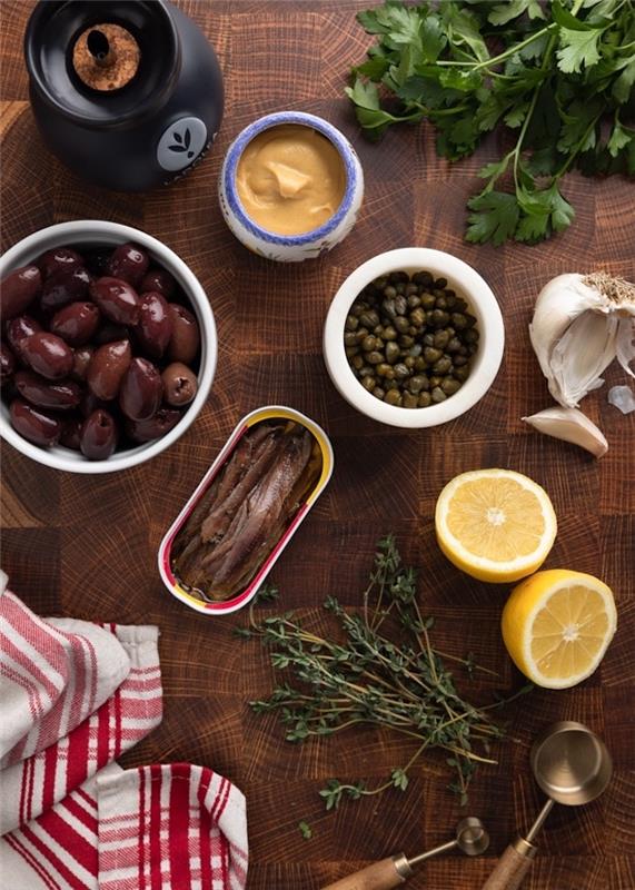 Siyah ve kırmızı bir masa örtüsü üzerinde kapari zeytin ve hamsi ürünleri ile yapılan Akdeniz yayılmış tepanade